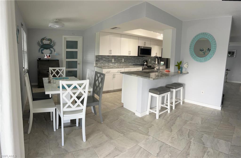 13511 Island Road Fort Myers, FL 33905 - Photo 14 of 38 a kitchen with a dining table chairs and a refrigerator