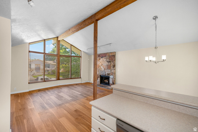 2088 Falcon Way Sandy, UT 84093 - Photo 12 of 46 Living area featuring vaulted ceilings with exposed wood beams, extensive window frontage, wood-finish flooring, and a stone fireplace