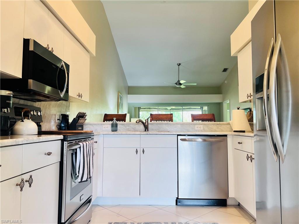 8073 Panther Trail, Unit 1404 Naples, FL 34113 - Photo 2 of 29 a kitchen with stainless steel appliances granite countertop a sink a stove a refrigerator and cabinets
