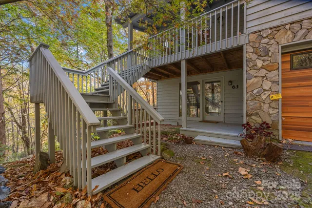 a view of a house with a small yard and wooden deck and furniture