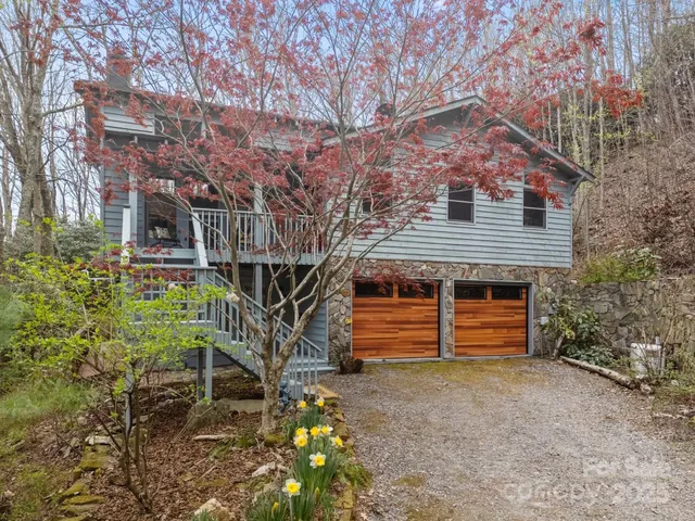 a backyard of a house with a large tree and wooden fence