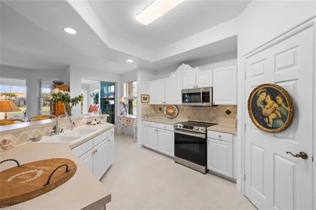 a kitchen with stainless steel appliances granite countertop a sink a stove top oven a refrigerator with white cabinets and wooden floor