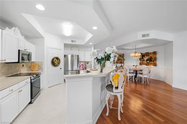 a kitchen with stainless steel appliances kitchen island granite countertop a table chairs and a wooden floor
