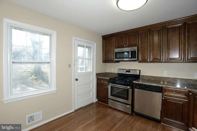 3816 Littleton Street Silver Spring, MD 20906 - Photo 21 of 21 a kitchen with granite countertop wooden cabinets stainless steel appliances and a window