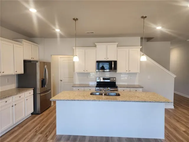 a kitchen with kitchen island a counter top space a refrigerator and cabinets