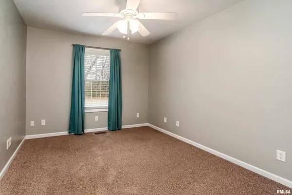 an empty room with chandelier fan and windows