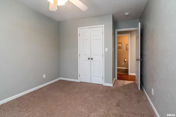 an empty room with a hallway and a chandelier fan