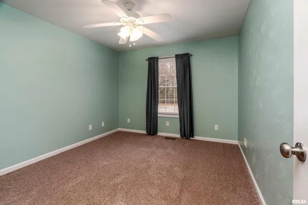 an empty room with chandelier fan and windows