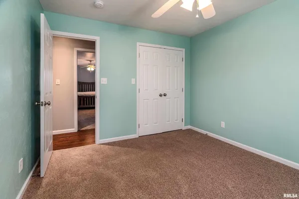 an empty room with closet and a chandelier fan