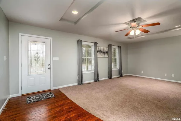 a view of an empty room with window and chandelier fan
