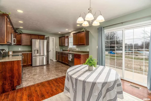 a kitchen with kitchen island granite countertop a stove top oven a sink dishwasher a dining table and chairs with wooden floor