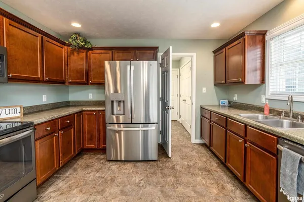 a kitchen with stainless steel appliances granite countertop a refrigerator a sink dishwasher a stove with wooden cabinets and floor