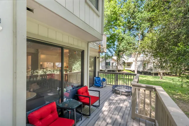 a view of a deck with couches and wooden floor next to a yard