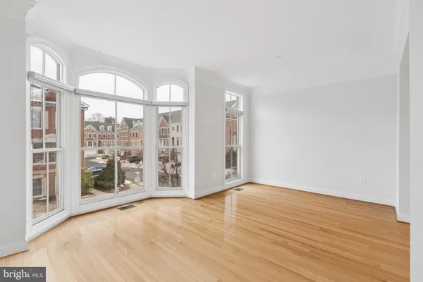 a view of an empty room with wooden floor and staircase