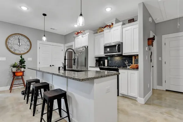 a kitchen with stainless steel appliances granite countertop a stove a sink a dining table and chairs