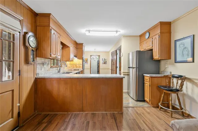 a kitchen with stainless steel appliances granite countertop a refrigerator a stove top oven a dining table and chairs with wooden floor