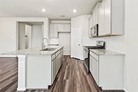 a kitchen with granite countertop a sink stove and refrigerator