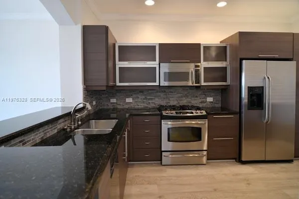 a kitchen with granite countertop stainless steel appliances and wooden cabinets