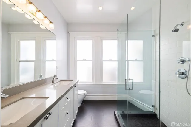 a view of a hallway with wooden floor and a bathroom