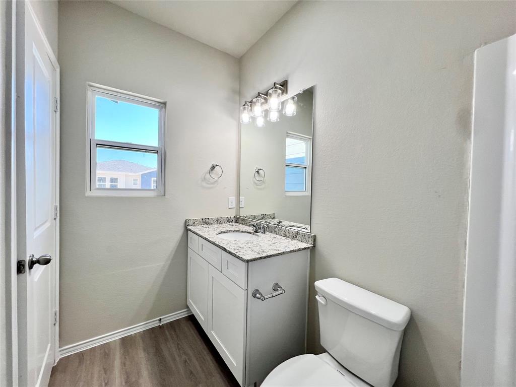 3501 East Renfro Street, Unit 120 Burleson, TX 76028 - Photo 18 of 30 a bathroom with a granite countertop toilet a sink and a mirror