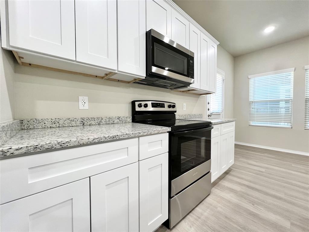 3501 East Renfro Street, Unit 120 Burleson, TX 76028 - Photo 7 of 30 a kitchen with stainless steel appliances granite countertop white cabinets granite counter tops and a wooden floors