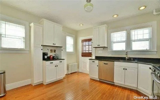 a kitchen with granite countertop a sink cabinets stainless steel appliances and a window