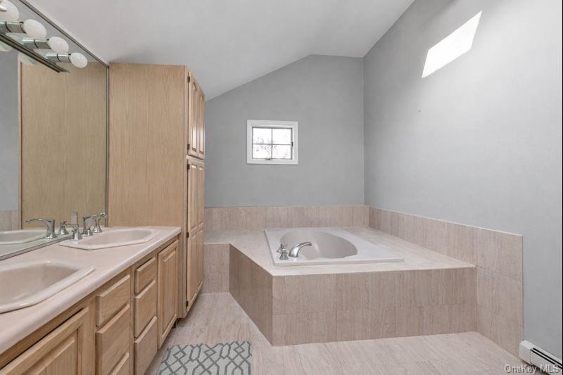 39 Fleets Cove Road Huntington, NY 11743 - Photo 14 of 20 Full bath featuring double vanity, a baseboard radiator, a garden tub, and vaulted ceiling