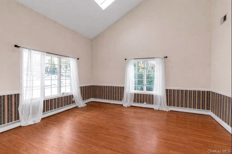 39 Fleets Cove Road Huntington, NY 11743 - Photo 4 of 20 Spare room with a wainscoted wall, high vaulted ceiling, a skylight, and light wood finished floors