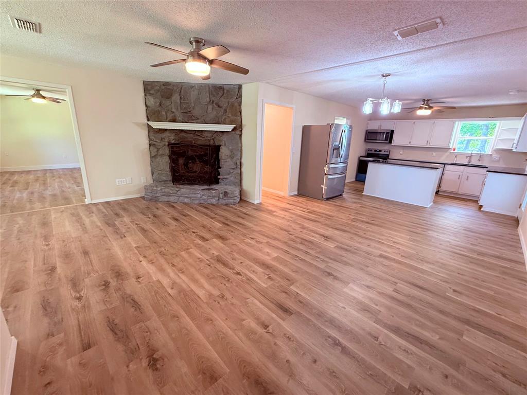 45 County Road 1197 Yantis, TX 75497 - Photo 6 of 26 a view of a livingroom with a fireplace a chandelier and wooden floor