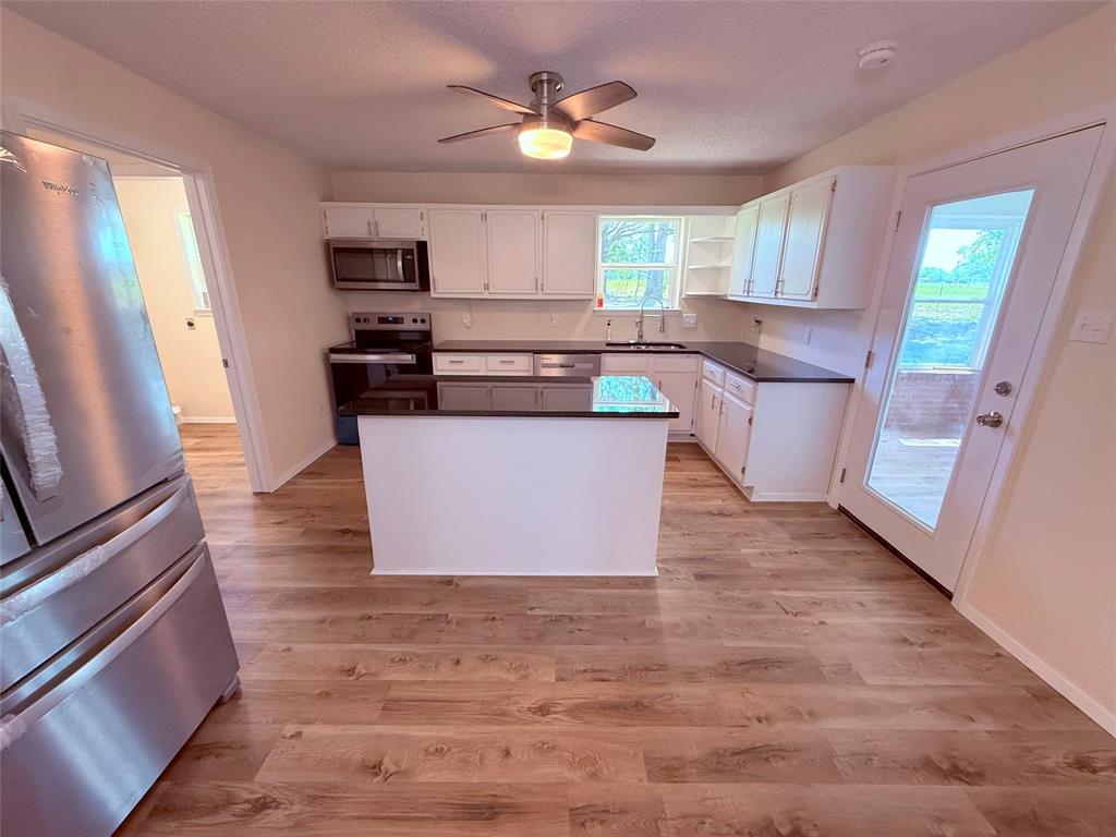 45 County Road 1197 Yantis, TX 75497 - Photo 7 of 26 a kitchen with stainless steel appliances granite countertop a stove a sink dishwasher a microwave oven a refrigerator with white cabinets and wooden floor