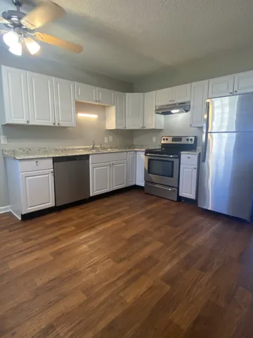 a kitchen with granite countertop a refrigerator stove top oven and sink