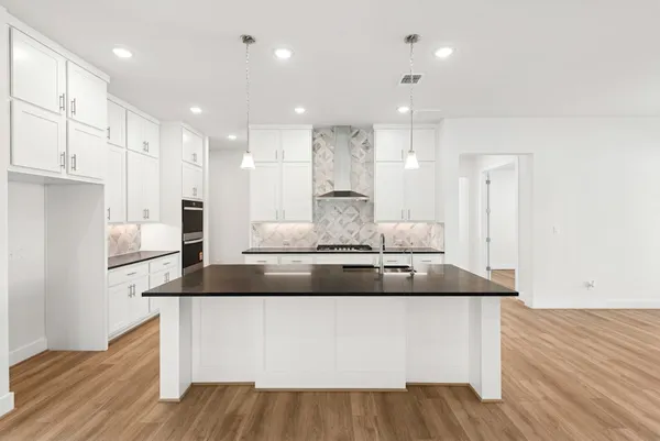 a large white kitchen with a large counter top and stainless steel appliances