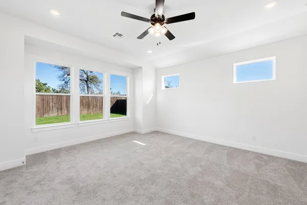 an empty room with windows and fan