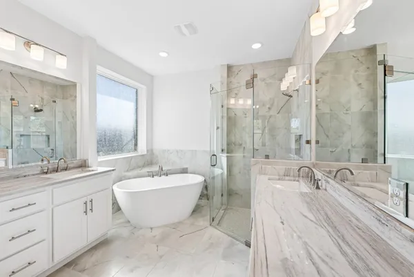 a spacious bathroom with a double vanity sink mirror and bathtub