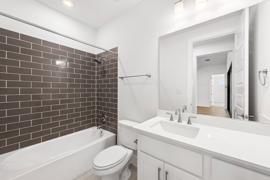 3332 Emerald Lake Path Georgetown, TX 78628 - Photo 29 of 35 a bathroom with a sink a toilet a mirror a bathtub and shower