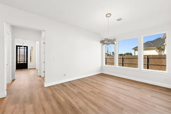 a view of an empty room with a window and wooden floor