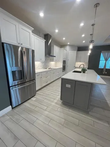 a kitchen with stainless steel appliances granite countertop a refrigerator a sink a stove and a oven