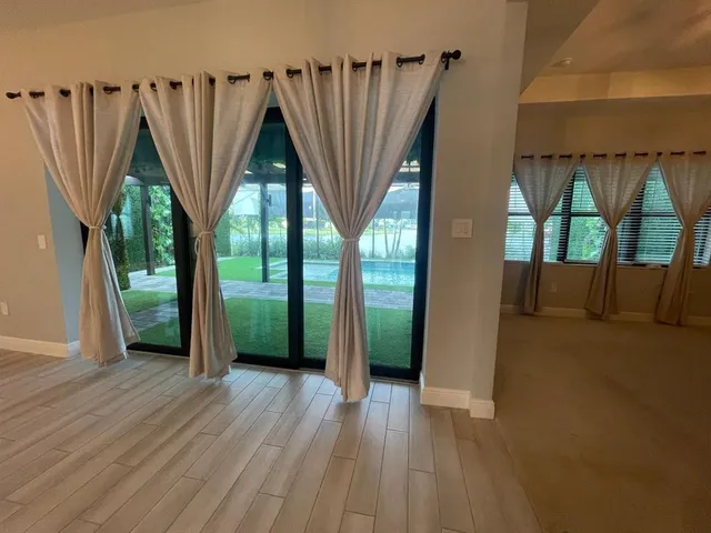 a view of a two room with wooden floor and windows