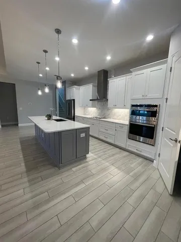 a large kitchen with stainless steel appliances kitchen island granite countertop a stove a sink and a refrigerator