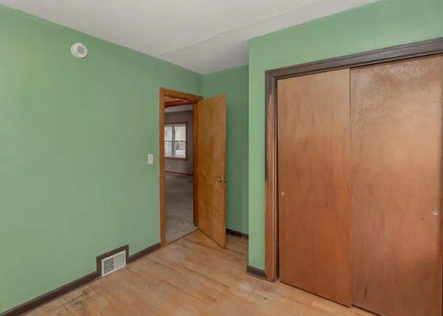 a view of an empty room with closet and wooden floor