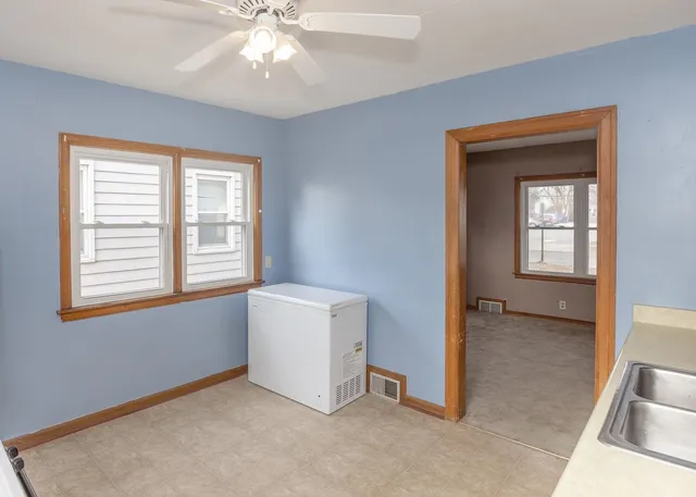 an empty room with windows and chandelier fan