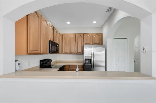 a kitchen with stainless steel appliances granite countertop a refrigerator a stove and a sink with wooden floor