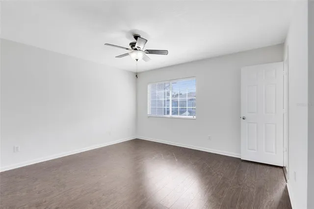 an empty room with wooden floor fan and windows