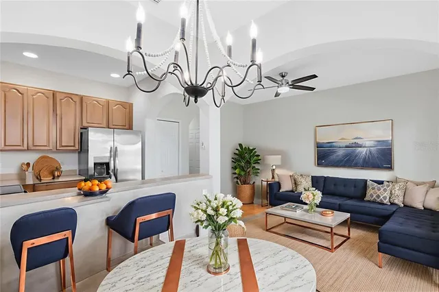 a living room with furniture kitchen view and a chandelier