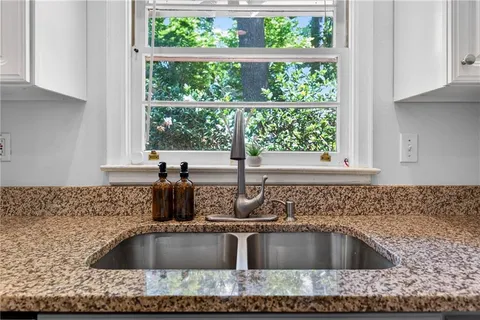a kitchen sink with granite countertop a sink window and cabinets