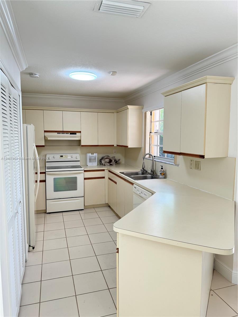 12913 Southwest 60th Street, Unit 12913 Miami, FL 33183 - Photo 6 of 17 a kitchen with cabinets a sink and white appliances