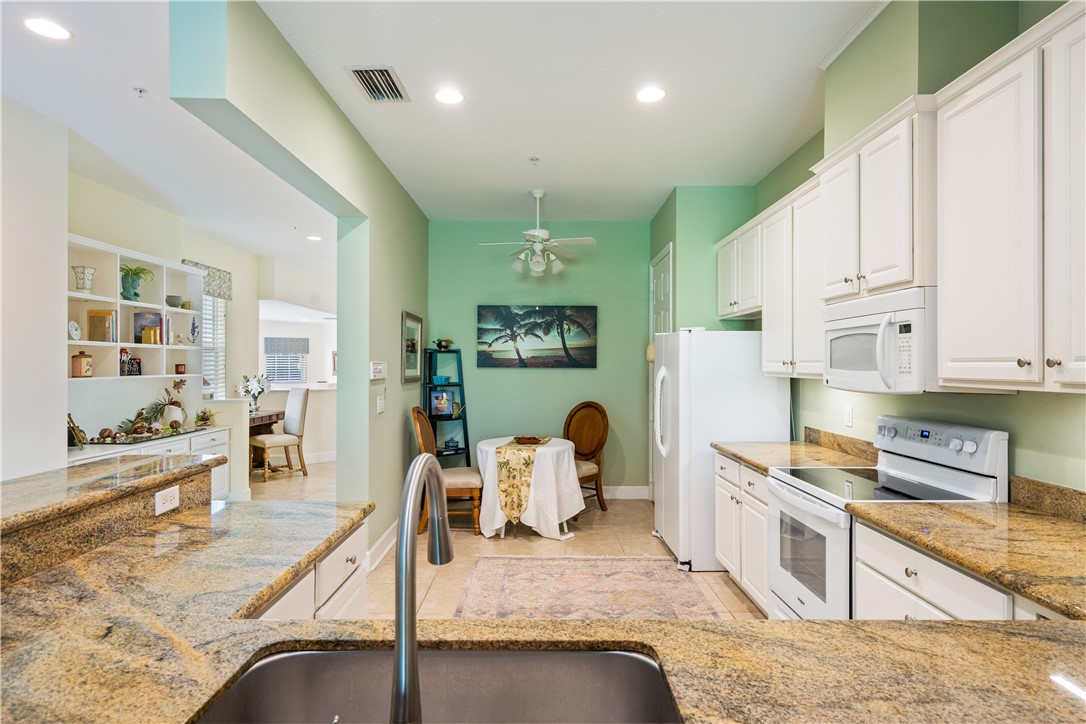 2340 Water Oak Court Southwest, Unit 223 Vero Beach, FL 32962 - Photo 9 of 36 a kitchen with kitchen island granite countertop a stove and white cabinets with wooden floor
