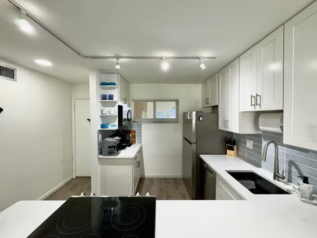 a kitchen with stainless steel appliances kitchen island granite countertop a refrigerator and a sink