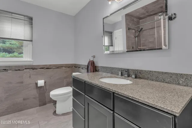 a bathroom with a granite countertop sink a toilet and a mirror