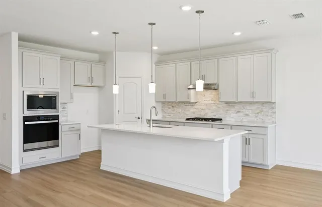 a large kitchen with stainless steel appliances granite countertop a stove a sink and a refrigerator